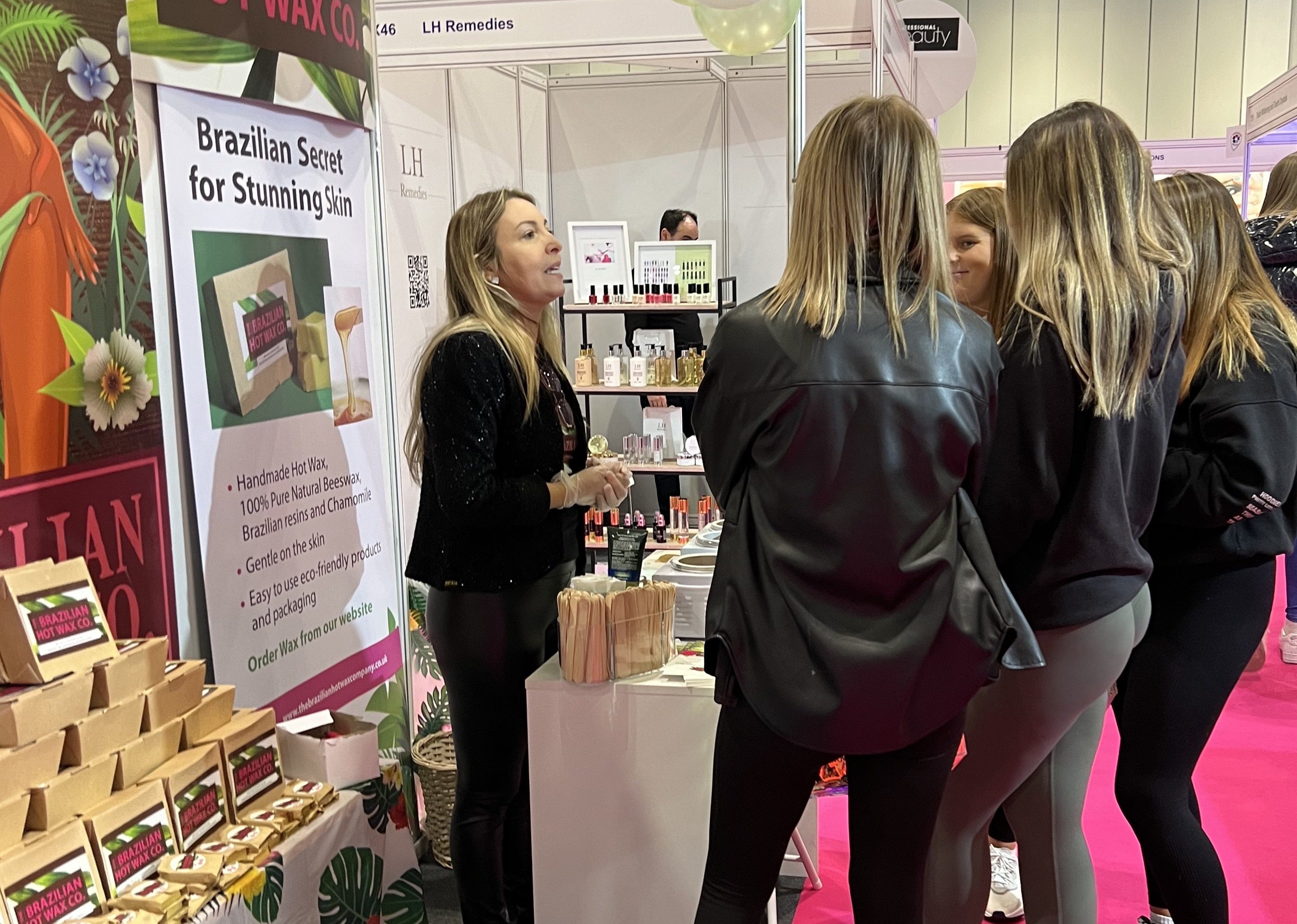 Women engaging at a beauty product booth at an expo or fair.