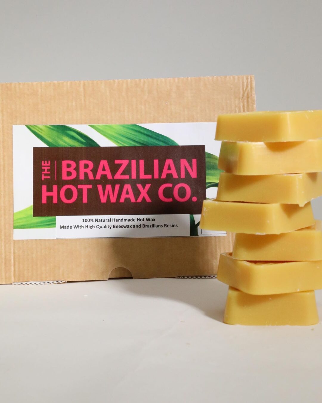 Stack of yellow wax bars next to a Brazilian Hot Wax Co. box.